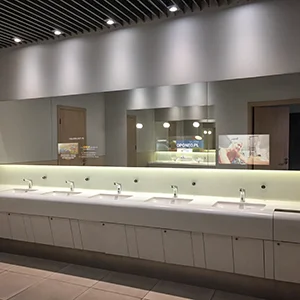 Photo of a bathroom in a shopping mall with advertisements displayed on mirrors above the sinks.